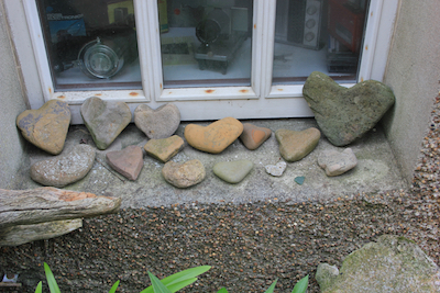 Collection of heart-shaped rocks outside the window, electronics collection inside the window; Stromness, Orkney, Scotland. Photo by Amanda Painter.  