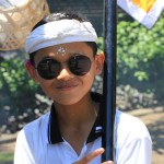 Boy in a funeral procession flashes the peace sign; the Balinese do not mind strangers witnessing their ceremonies. Karma and dharma are a strong part of their Hindu beliefs. Photo by Amanda Painter.